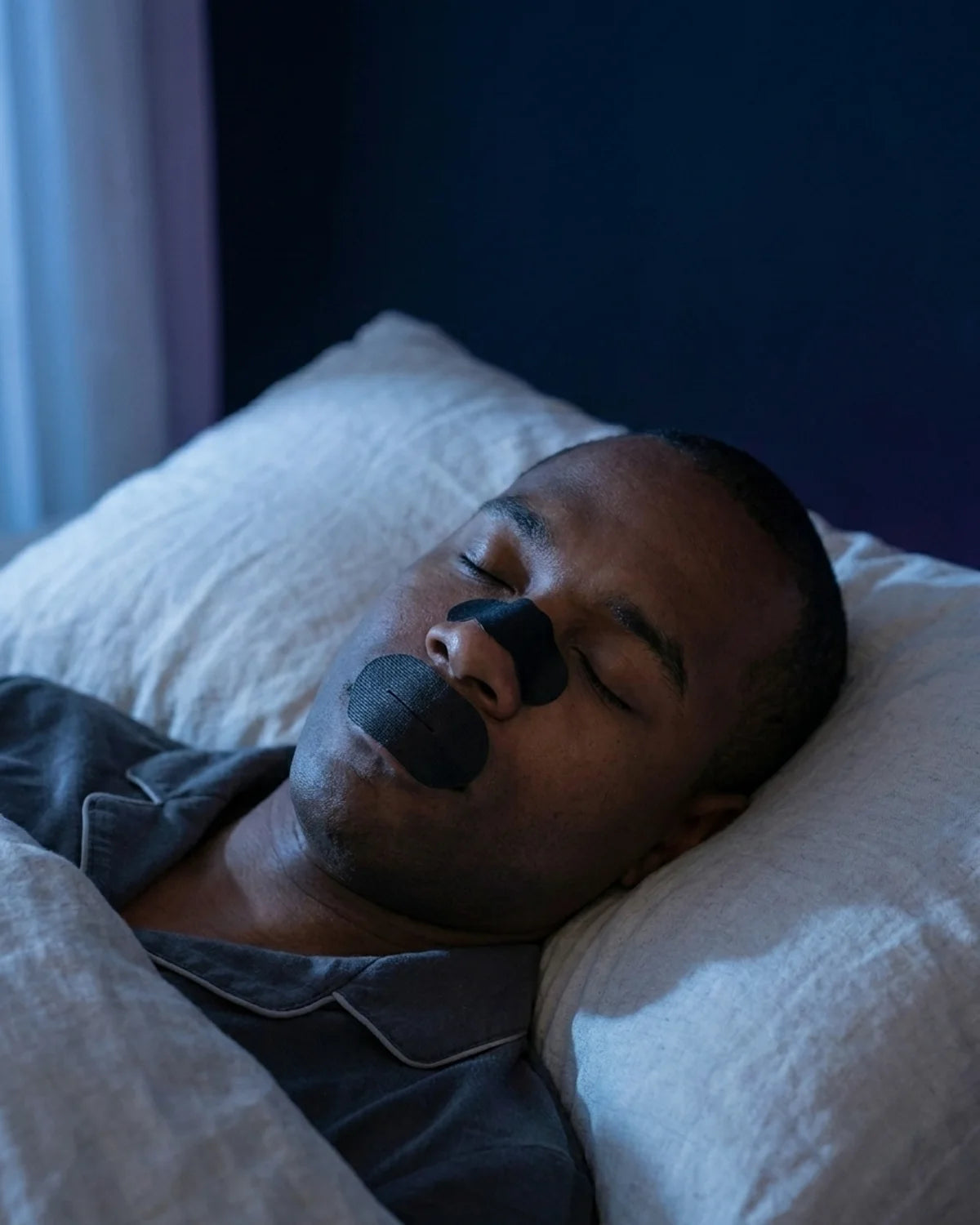 Man asleep wearing AXONRYTE nasal strip and mouth tape, peaceful night breathing